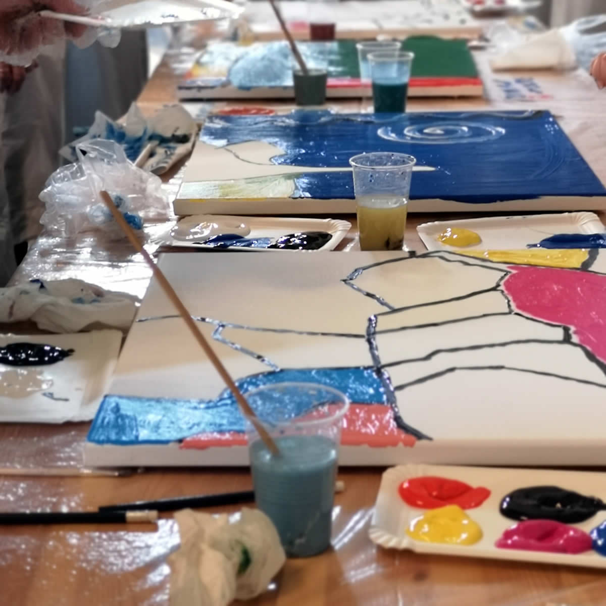 Team gestaltet gemeinsam ein großes Firmenkunstwerk beim kreativen Teambuilding mit Kunst